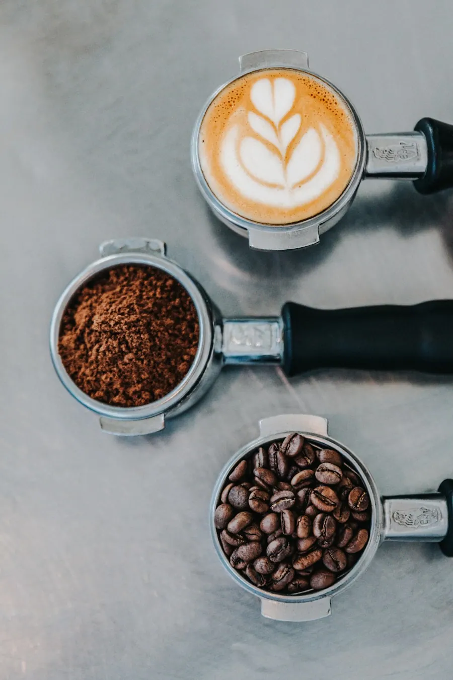 Portafiltru plin cu cafea proaspăt măcinată, văzut de sus, lângă boabe întregi